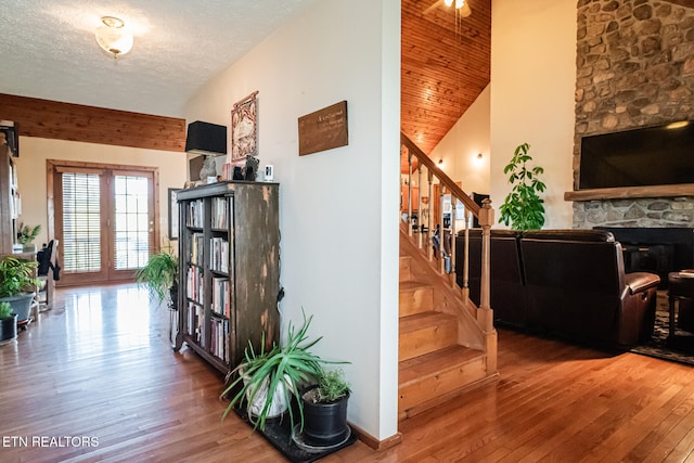 stairs featuring a stone fireplace, hardwood / wood-style floors, french doors, and a textured ceiling