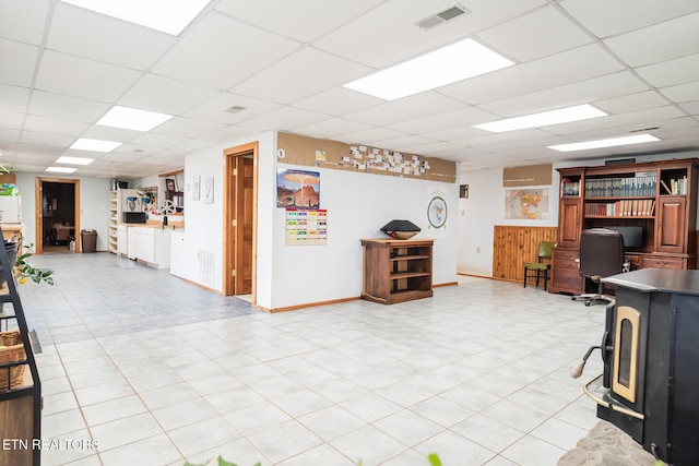 interior space with a wood stove and a drop ceiling