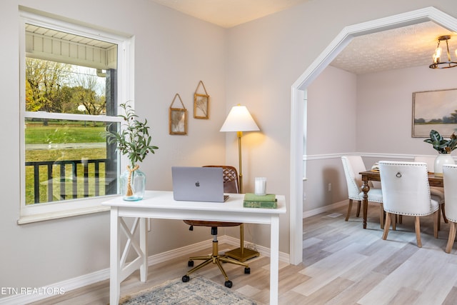 office area featuring a textured ceiling, light hardwood / wood-style floors, and an inviting chandelier