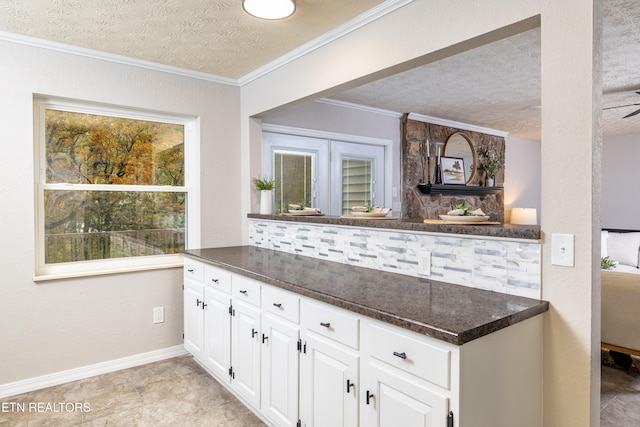 kitchen featuring white cabinets, a textured ceiling, crown molding, and tasteful backsplash