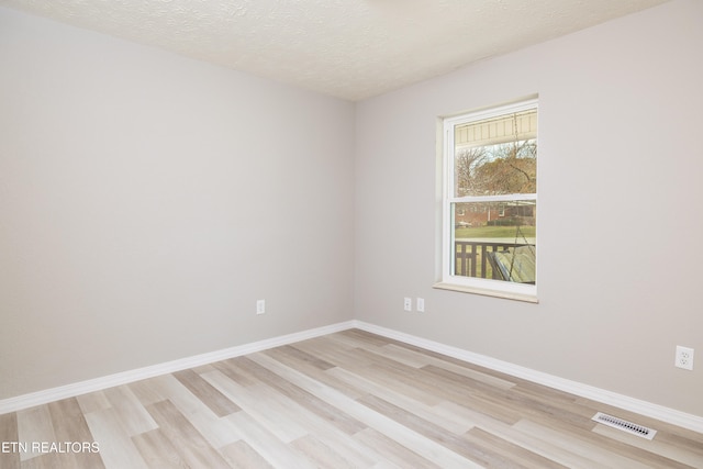 empty room with a textured ceiling and light wood-type flooring