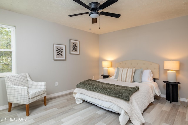 bedroom featuring a textured ceiling, light wood-type flooring, and ceiling fan