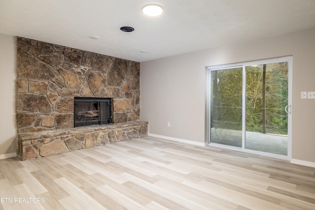 unfurnished living room with light hardwood / wood-style floors and a stone fireplace