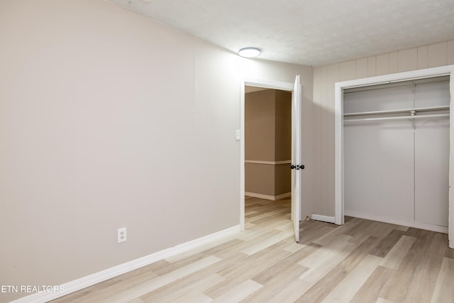 unfurnished bedroom with a closet, a textured ceiling, and light hardwood / wood-style flooring