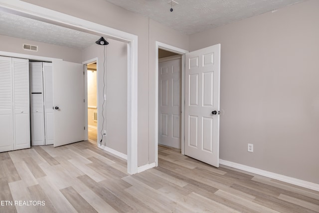 unfurnished bedroom with a closet, light hardwood / wood-style floors, and a textured ceiling