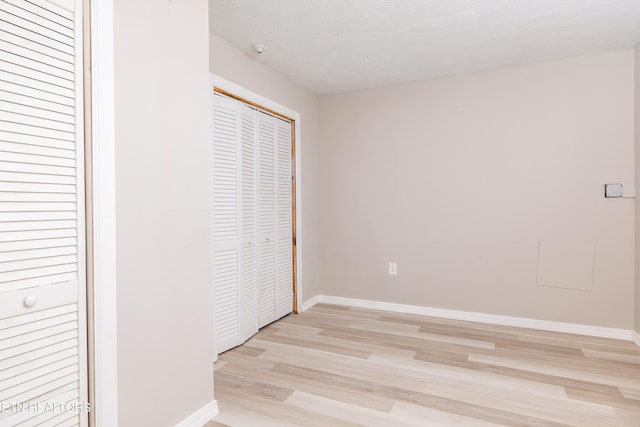 unfurnished bedroom with a closet, a textured ceiling, and light hardwood / wood-style flooring