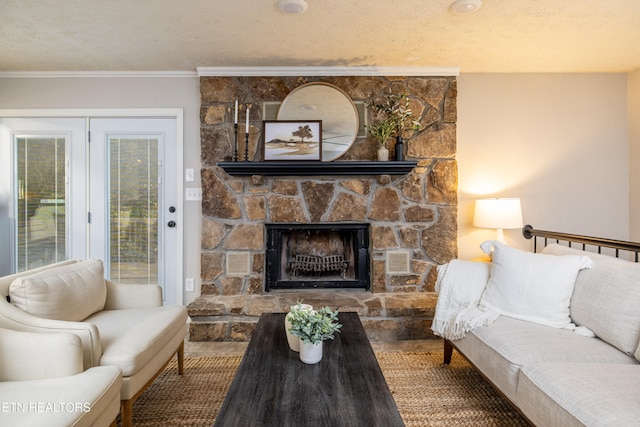 living room featuring a textured ceiling, a stone fireplace, crown molding, and hardwood / wood-style floors