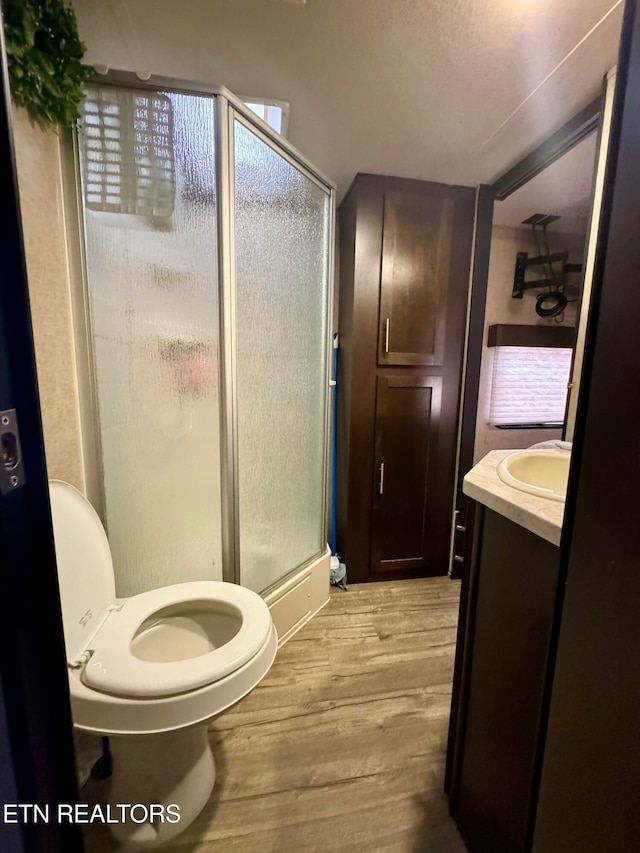 bathroom featuring walk in shower, vanity, a textured ceiling, hardwood / wood-style floors, and toilet