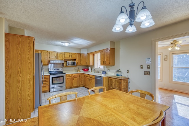 kitchen featuring appliances with stainless steel finishes, a textured ceiling, hanging light fixtures, sink, and ceiling fan with notable chandelier