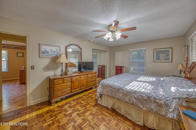 bedroom with ceiling fan, a textured ceiling, a closet, and parquet floors