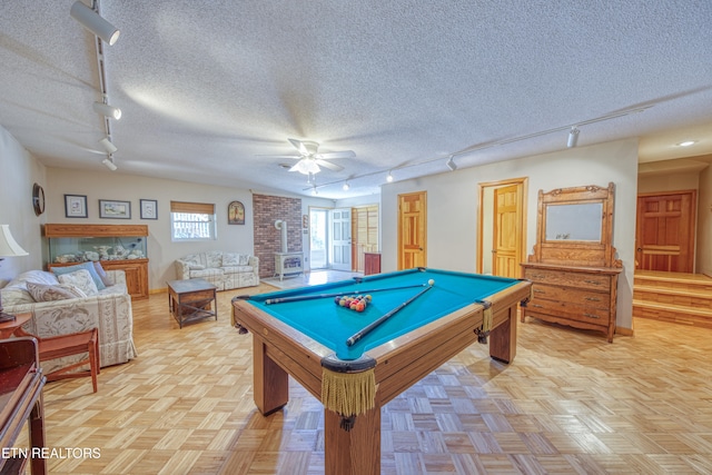 playroom featuring pool table, track lighting, a wood stove, and a textured ceiling