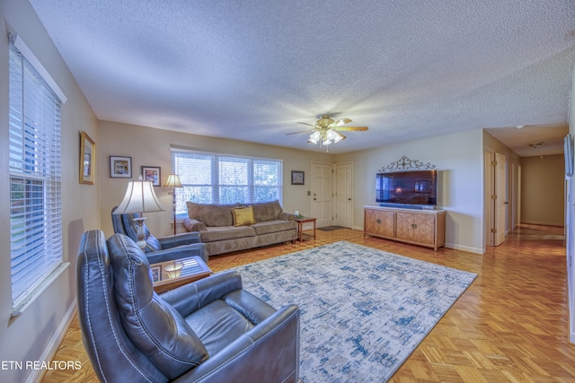 living room with ceiling fan, a textured ceiling, and light parquet flooring