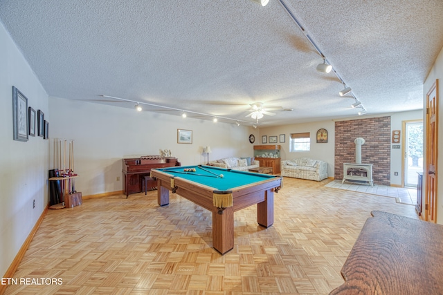 rec room with pool table, a wood stove, a textured ceiling, rail lighting, and light parquet flooring