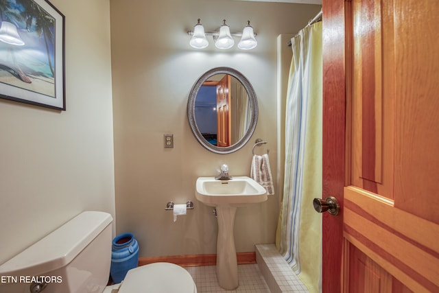 bathroom featuring curtained shower, tile patterned floors, and toilet