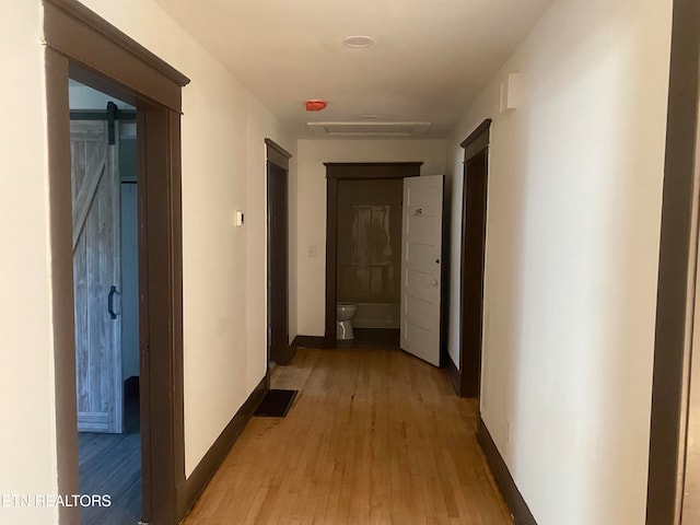 hall featuring a barn door and light hardwood / wood-style flooring