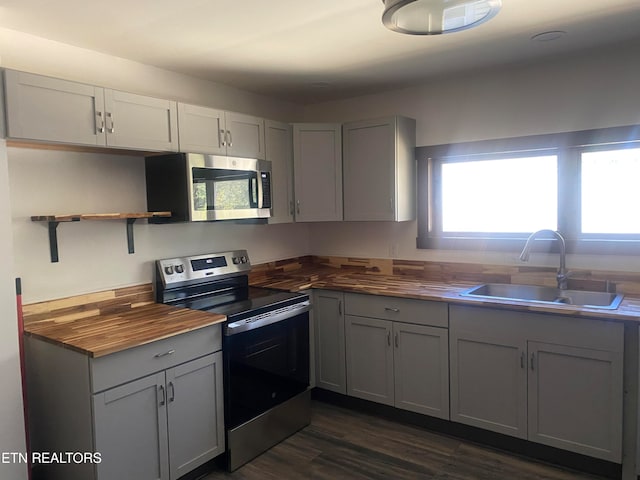 kitchen with stainless steel appliances, butcher block counters, sink, and dark wood-type flooring