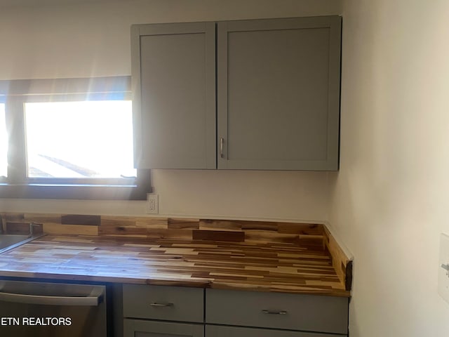 kitchen featuring dishwasher, butcher block countertops, and gray cabinetry