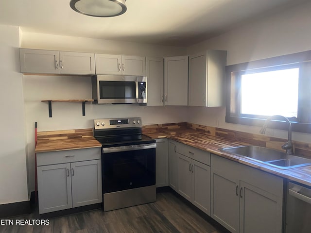 kitchen featuring stainless steel appliances, dark wood-type flooring, sink, and wood counters