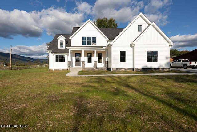 modern inspired farmhouse with a front lawn, a mountain view, and a porch