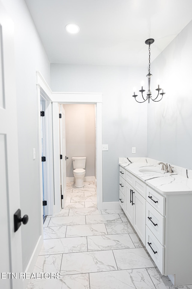 bathroom with toilet, vanity, and a chandelier