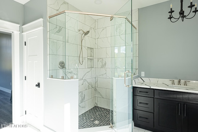 bathroom with vanity, an inviting chandelier, and a shower with door