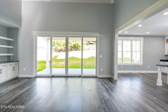 unfurnished living room with dark wood-type flooring and a towering ceiling