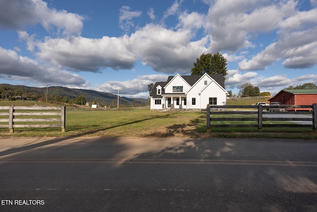 view of front of property with a mountain view, a front yard, and a rural view