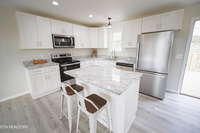 kitchen with pendant lighting, sink, a kitchen island, white cabinetry, and appliances with stainless steel finishes