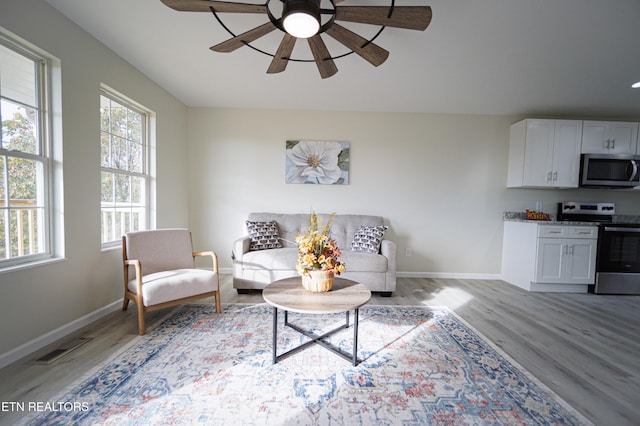 living room featuring ceiling fan, plenty of natural light, and light hardwood / wood-style flooring