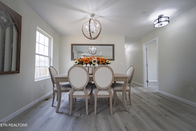 dining space with light wood-type flooring and a notable chandelier