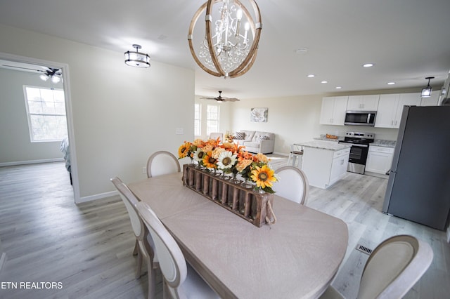 dining area with light hardwood / wood-style floors, ceiling fan with notable chandelier, and plenty of natural light