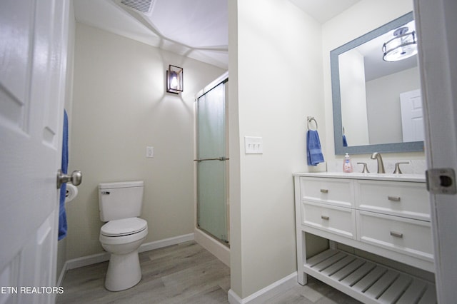 bathroom with hardwood / wood-style floors, vanity, toilet, and a shower with shower door