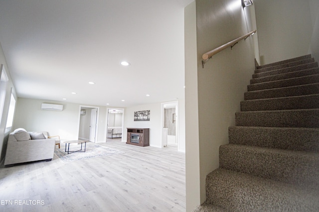 stairway featuring a wall unit AC and wood-type flooring