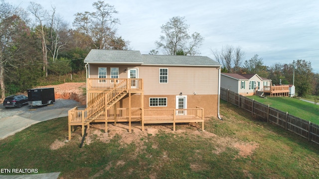 rear view of house featuring a lawn and a wooden deck