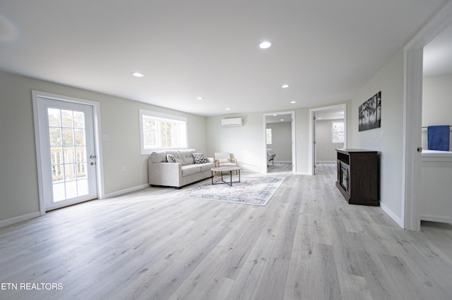 living room with light wood-type flooring and a wall mounted air conditioner