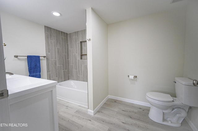 full bathroom with wood-type flooring, tiled shower / bath combo, toilet, and vanity