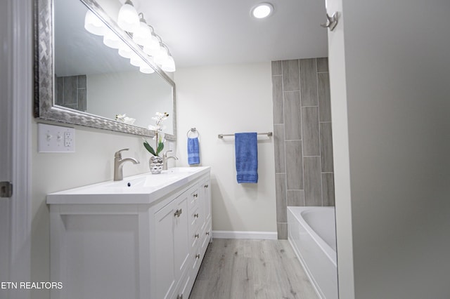 bathroom featuring tiled shower / bath, vanity, and wood-type flooring