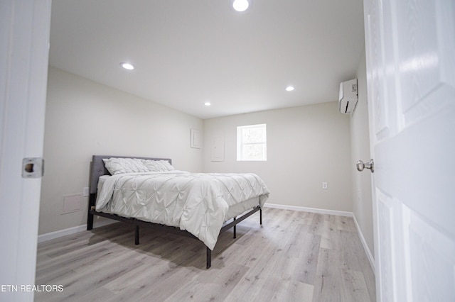 bedroom with light hardwood / wood-style floors and a wall mounted air conditioner