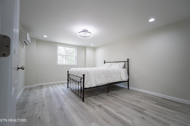 bedroom with a wall mounted air conditioner and light hardwood / wood-style floors