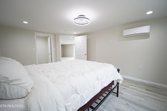 bedroom featuring a wall mounted air conditioner and light hardwood / wood-style floors