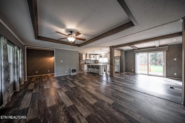 unfurnished living room featuring dark hardwood / wood-style flooring, a textured ceiling, ceiling fan, and a raised ceiling