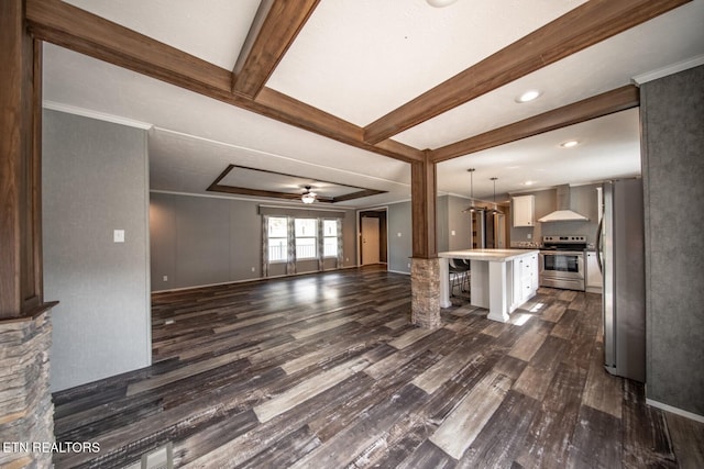 unfurnished living room featuring beamed ceiling, ceiling fan, dark hardwood / wood-style floors, and crown molding