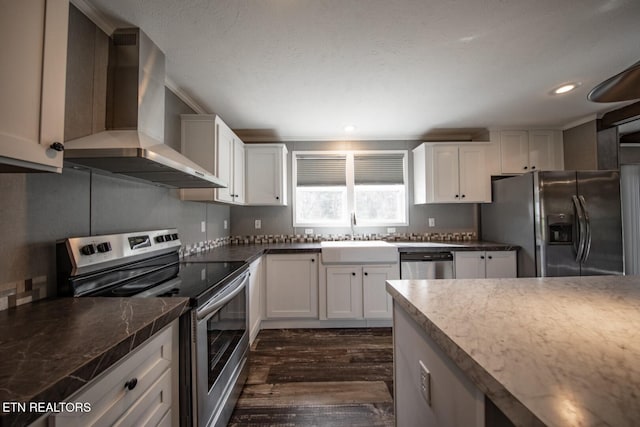 kitchen featuring stainless steel appliances, sink, white cabinets, wall chimney range hood, and dark hardwood / wood-style flooring