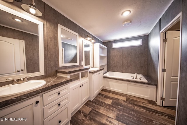 bathroom with hardwood / wood-style floors, a tub to relax in, a textured ceiling, and vanity