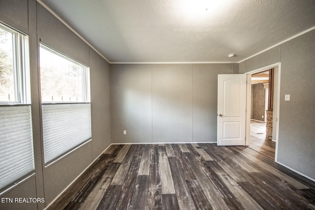 unfurnished room with a textured ceiling, ornamental molding, and dark hardwood / wood-style floors