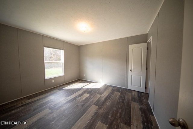 unfurnished room featuring dark hardwood / wood-style flooring and a textured ceiling