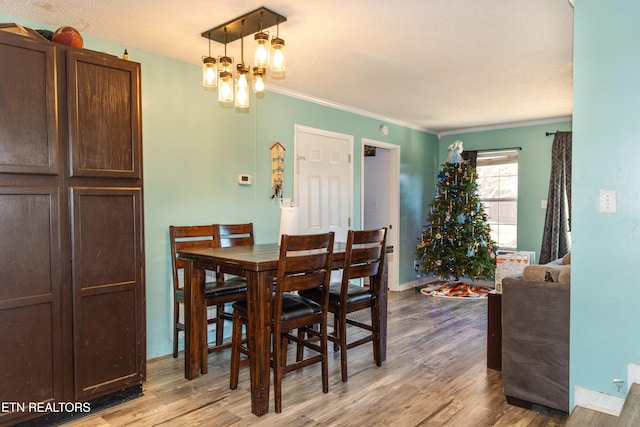 dining space featuring a notable chandelier, light hardwood / wood-style floors, and ornamental molding