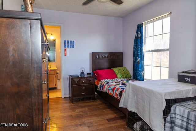 bedroom with ceiling fan, dark wood-type flooring, and a textured ceiling