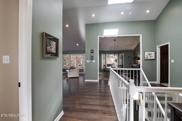 corridor with a skylight, dark hardwood / wood-style flooring, a high ceiling, and a notable chandelier