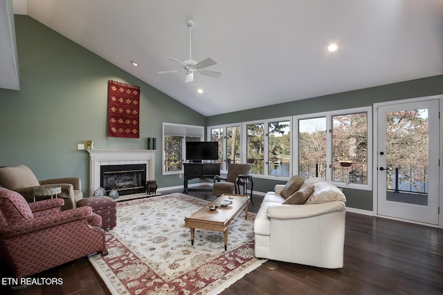 living room with lofted ceiling, a tiled fireplace, dark hardwood / wood-style floors, and ceiling fan